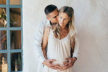 A man hugs a pregnant woman, a loving couple is expecting the birth of a baby.
