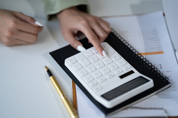 Close-up:  Hands Calculating Financial Success: A professional woman's hands meticulously calculate figures on a calculator.