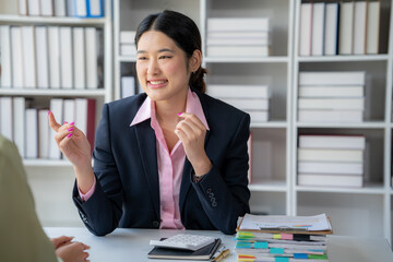 Confident Businesswoman in Meeting: A young businesswoman in a navy blue blazer and pink blouse,...