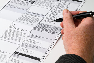 Obraz premium Absentee voter holding pen in hand choosing in US General Election