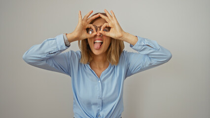 Young woman in blue shirt making glasses gesture with hands over white background