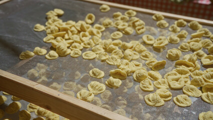 Orecchiette pasta drying outdoors on a wooden frame in bari, puglia, italy, highlighting traditional italian cuisine and local food preparation.