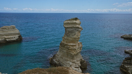Stunning rock formation in the turquoise waters of salento's coastline in torre dell'orso, puglia, italy under a clear blue sky.