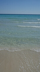 Beautiful clear water and sandy beach of porto cesareo in puglia, italy under a bright blue sky with gentle waves lapping the shore.