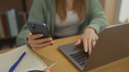 A young woman multitasks with a smartphone and laptop at home displaying productivity and connectivity.