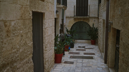 A young woman in a striped shirt walks through a charming narrow street in polignano a mare, puglia, italy, surrounded by stone buildings and potted plants.