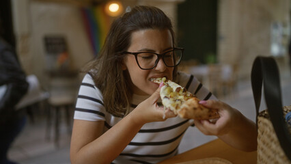 Hispanic woman enjoying pizza at an outdoor terrace restaurant in italy, capturing a vibrant and casual dining moment.