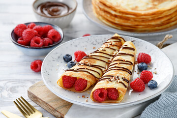 Crepes or thin pancakes with cottage cheese filling, fresh berries and chocolate sauce , sprinkled with nuts