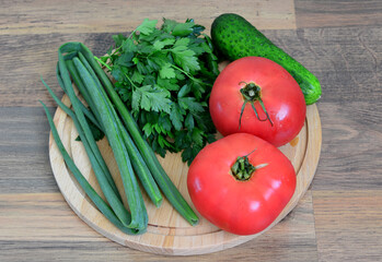 a wooden cutting board with tomatoes, cucumber, green onion and parsley