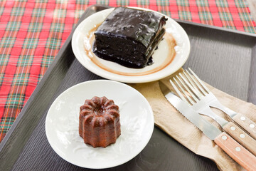 Homemade Canelés and Fudgy brownies on plate, traditional French sweet dessert,selective focus.