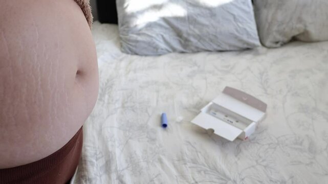 A young woman preperes her belly and gives an injection to herself