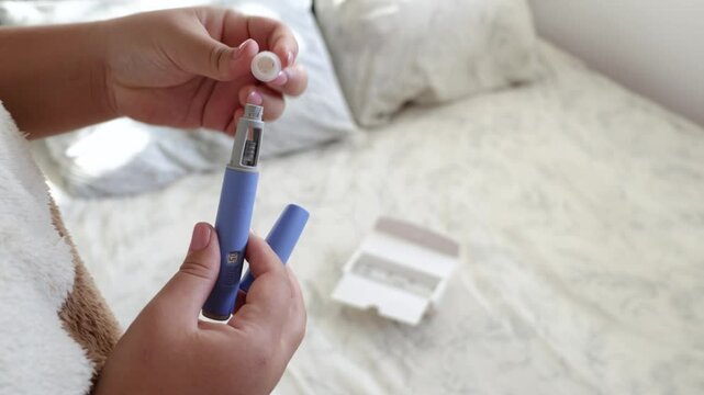 A young woman screws a needle on pre-filled pen injector to prepare it for taking medicine