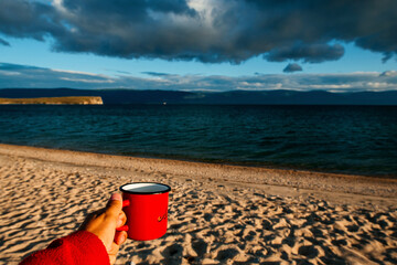 red mug with coffee or tea by the sea