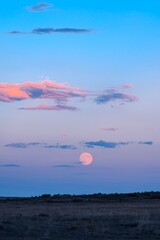 HDR October Supermoon Rise at Sunset with colorful clouds, pink and blue cotton candy sunset at dusk in Wyoming super moon