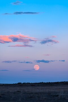 HDR October Supermoon Rise at Sunset with colorful clouds, pink and blue cotton candy sunset at dusk in Wyoming super moon