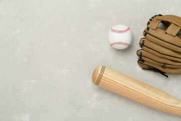 Baseball glove and bat with ball on concrete background, top view