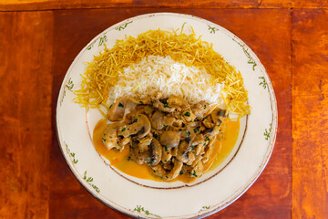 Traditional chicken stroganoff with mushrooms, straw potatoes and white rice