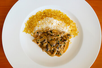 Traditional chicken stroganoff with mushrooms, straw potatoes and white rice