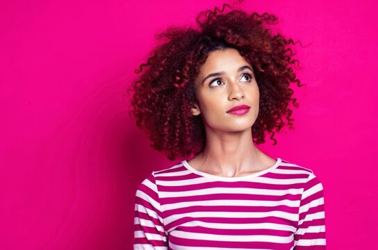 Photo of positive woman with curly hair dressed striped top look directing at proposition empty space isolated on pink color background