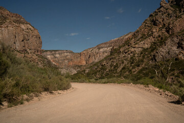 Travel. View of the dirt road across the arid desert and colorful rock formations.