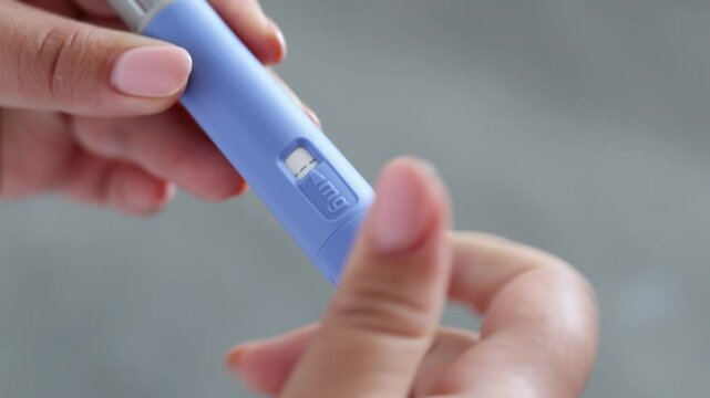 A super close up of a young woman priming the pen injector, prepering it for injection