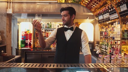 Smart bartender chilling glass with ice for serving drink to customer at beverage bar counter welcome drink with charm professionalism making great first impression greeting guess at club. Vinosity.