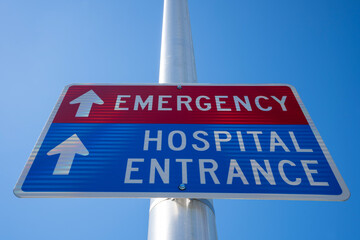Low angle view of the Emergency and Hospital Entrance directional signage on a post against clear blue sky.