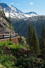 A scenic passenger train rounding a curve high in the mountains  above Skagway, Alaska