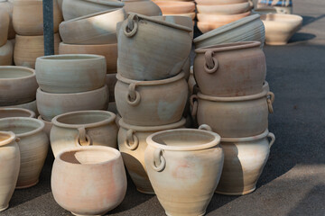 Perfect ceramic pots for trees or flowers. A variety of large clay pots in different shapes and sizes, neatly arranged outside a garden supply store, ideal for gardening and landscaping projects.