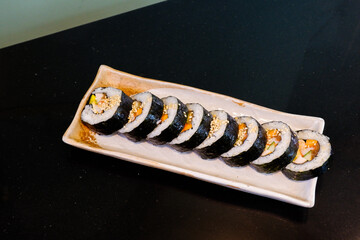 Kimbap on white plate and radish,Gimbap is Korean seaweed rice roll filled with a variety of delicious fillings, egg, carrot, ham, tuna,gochujang sauce,served with kimchi, The street food of Korea..