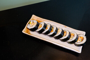 Kimbap on white plate and radish,Gimbap is Korean seaweed rice roll filled with a variety of delicious fillings, egg, carrot, ham, tuna,gochujang sauce,served with kimchi, The street food of Korea..