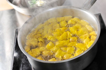 Ravioli del plin, typical pasta from Langhe, Piedmont, Italy - agnolotti cooked in boiling water in pot on induction plate