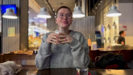 young beautiful woman with short haircut in coffee shop, drinking coffee and enjoying atmosphere