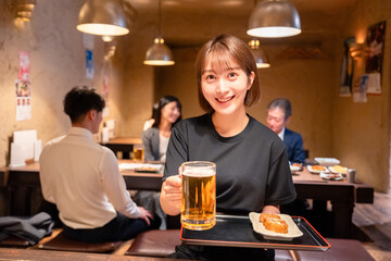 ビールを提供する居酒屋の女性スタッフ