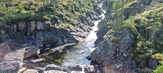 fresh mountain water stream running through a steep v shaped valley in norway