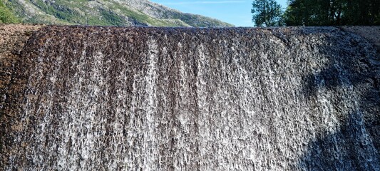 water flowing over small concrete dam connected to hydro electrical power production