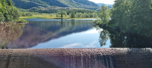 water flowing over small concrete dam connected to hydro electrical power production