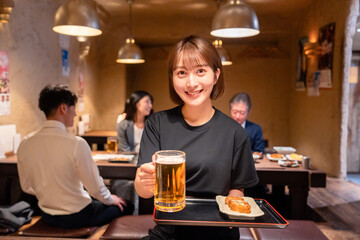 ビールを提供する居酒屋の女性スタッフ