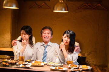 宴会の席で女性と肩を組むビジネスマン