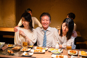 宴会の席で女性と肩を組むビジネスマン