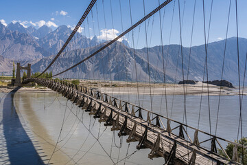 Scenic perspective view of ancient wooden suspension bridge over Shyok river near Khaplu, Ghanche, Gilgit-Baltistan, Pakistan