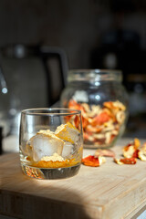 Preparation of fly agaric drink, ground powdered dry mushroom on ice cubes in a glass, illuminated by natural sunlight.  Homemade fly agaric elixir.  