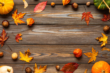 Autumn and Thanksgiving composition. Frame made of pumpkins, fall dried leaves, flowers, nuts, chestnuts on rustic wooden background. Flat lay. Top view with copy space