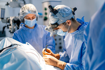 Surgeons in a complex hospital operation. Two surgeons in scrubs and masks focus on a detailed...
