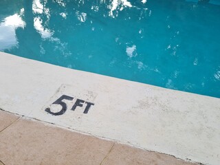 5 feet depth of a swimming pool written in black letters on the edge of the pool