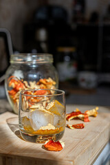 Preparation of fly agaric drink, ground powdered dry mushroom on ice cubes in a glass, illuminated by natural sunlight.  Homemade fly agaric elixir.  