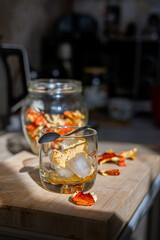 Preparation of fly agaric drink, ground powdered dry mushroom on ice cubes in a glass, illuminated by natural sunlight.  Homemade fly agaric elixir.  