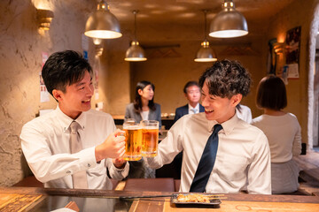 居酒屋でビールを飲む二人の若手ビジネスマン