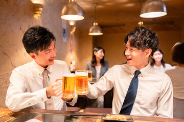 居酒屋でビールを飲む二人の若手ビジネスマン