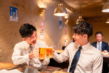 居酒屋でビールを飲む二人の若手ビジネスマン